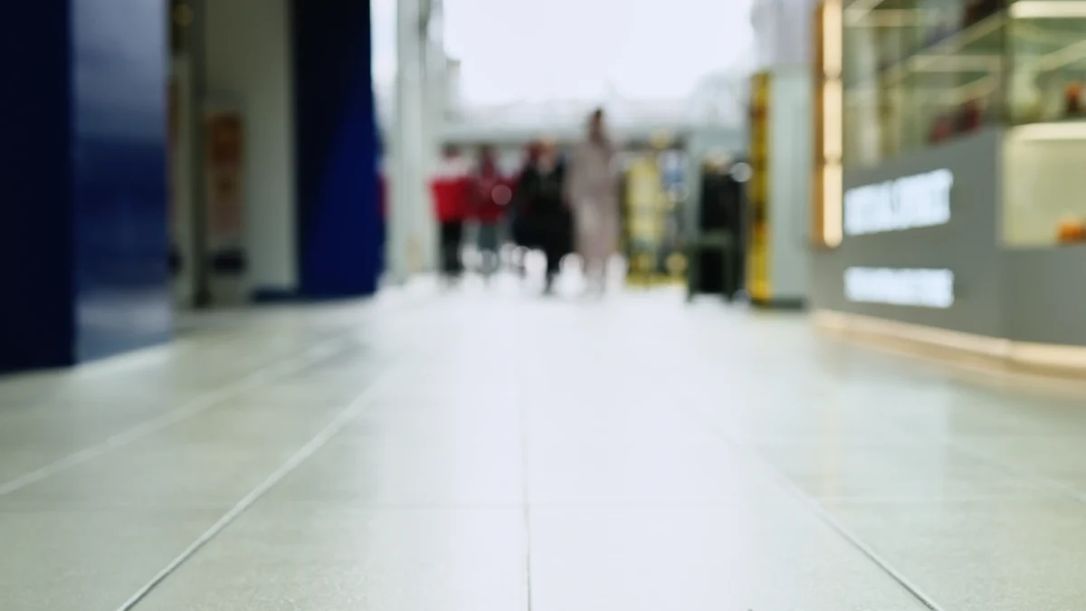 Low view along a shopping centre corridor with a polished tiled floor and shoppers in the distance