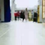 Low view along a shopping centre corridor with a polished tiled floor and shoppers in the distance