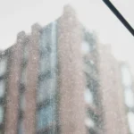 Dusty, streaked window glass with a red brick building reflected behind it