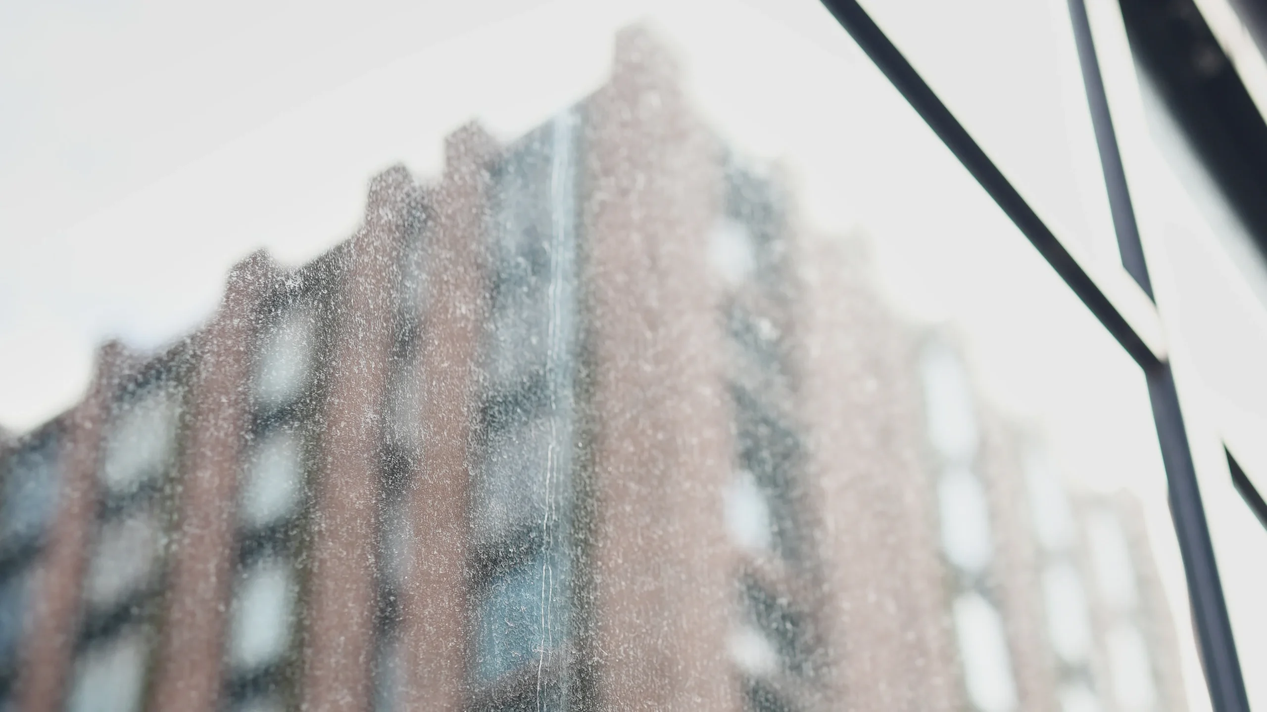 Dusty, streaked window glass with a red brick building reflected behind it